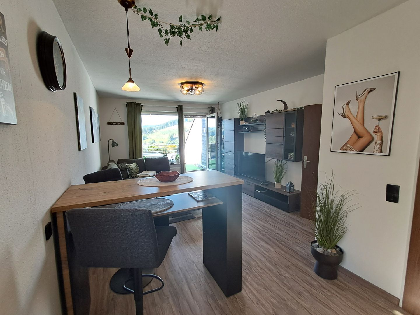 A modern kitchen with a wooden island, bar stools, and a view of the outdoors.