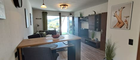 A modern kitchen with a wooden island, bar stools, and a view of the outdoors.