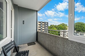A balcony with a bench, a door, and a view of buildings and trees. - CASATUA Blue Design - Calm - Workspace - Balcony - Trade Show - WiFi (Wuppertal)