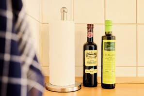 A kitchen counter with a paper towel holder, a bottle of Mazzetti balsamic vinegar, and a bottle of Francescane extra virgin olive oil.