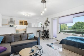 A modern apartment with a living room, kitchen, and balcony.