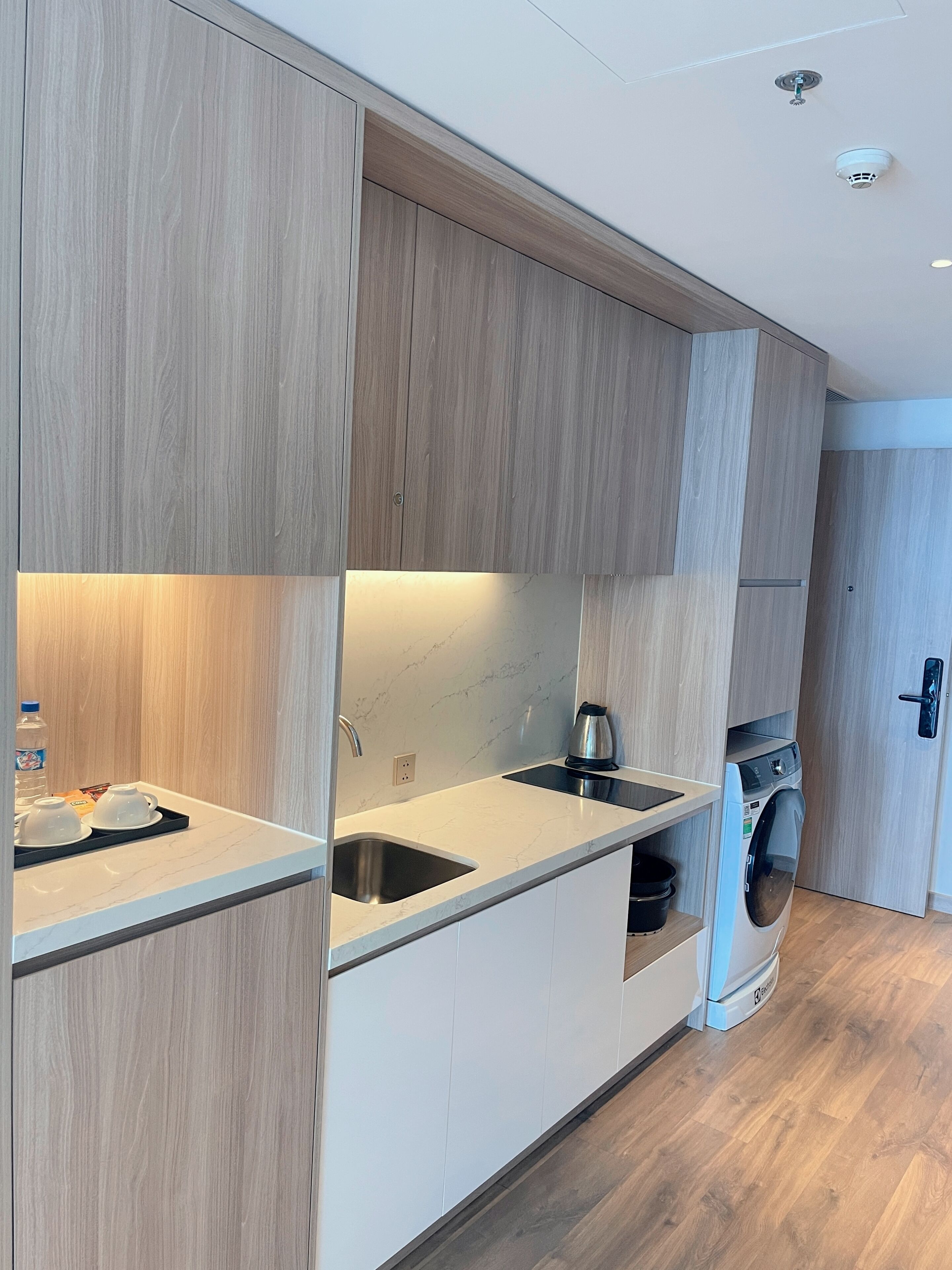 A modern kitchen with wooden cabinets, a built-in dishwasher, and a stainless steel sink.