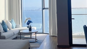 A modern living room with a large window, a sofa, a coffee table, and a view of the sea. - Sea view Àlacarte Ha Long Bay Apartment (Bai Chay)