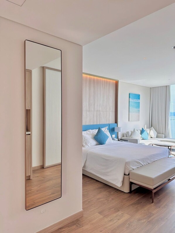 A modern hotel room with a large bed, a seating area, and a large mirror.