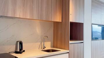 Una cocina moderna con armarios de madera, un lavamanos de acero inoxidable y una estufa empotrada.