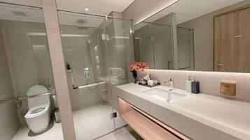 A modern bathroom with a glass-enclosed shower, a white sink, and a large mirror.