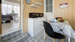 Eine kompakte Küche mit Mikrowelle, kleinem Kühlschrank und einer Essecke mit Tisch und Stühlen.