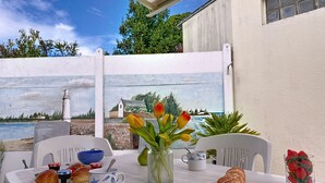 Ein Tisch gedeckt mit Brot, einer Banane, einem Laib Brot, einer Schüssel Erdbeeren, einer Vase mit Tulpen und einer Tasse mit einem Löffel.