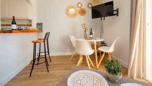 Un espacio moderno para vivir con cocina, comedor y un televisor de pantalla plana montado en la pared.