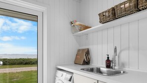 A laundry room with a washing machine, a sink, and a window overlooking a grassy area. - "Gertje" - 20m from the sea by Interhome (Assens)