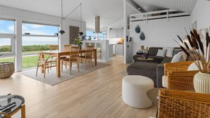 A spacious living area with a dining table, sofas, and a view of the outdoors. - "Gertje" - 20m from the sea by Interhome (Assens)