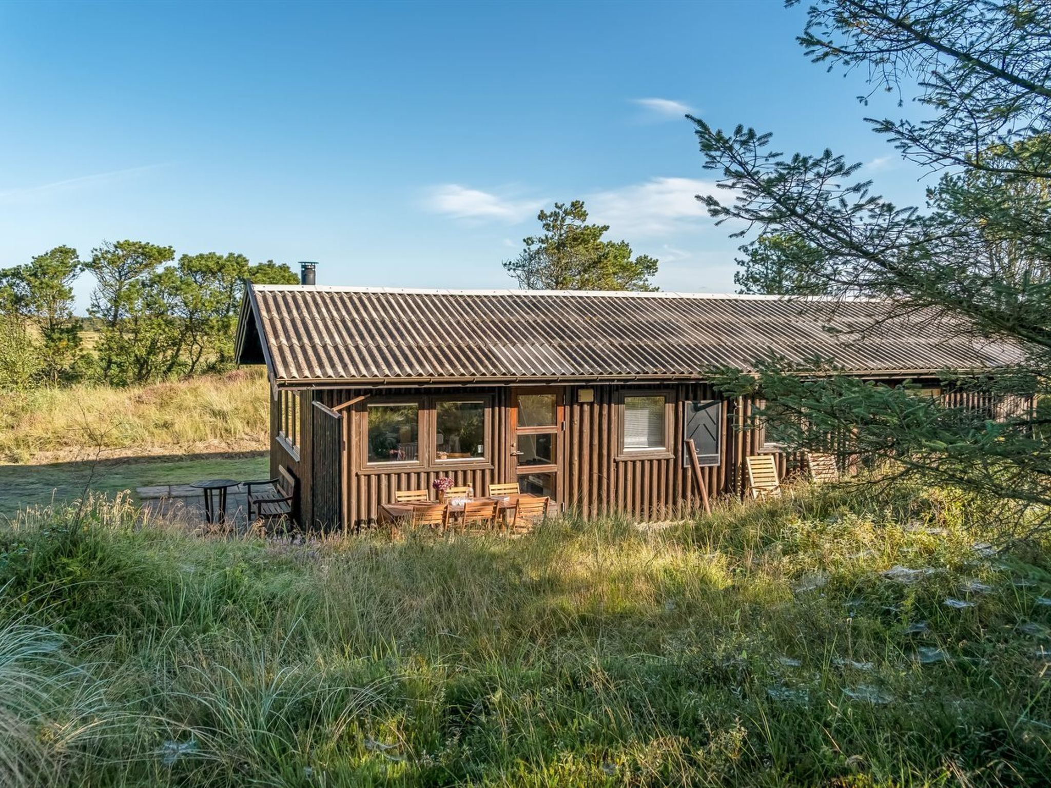 A rustic cabin with a metal roof, wooden walls, and a porch with benches.