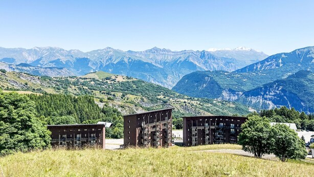 A mountainous landscape with three modern buildings in the foreground. - Les Pistes by Interhome (Le Corbier)