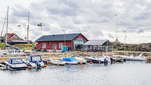 A harbor with boats docked, a red building with a sign reading "VÅRVE", and a clear sky.