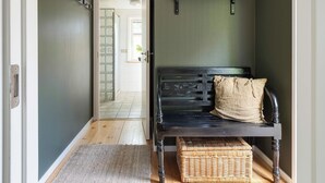 A hallway with a wooden bench, a wicker basket, and a wall-mounted plant shelf.
