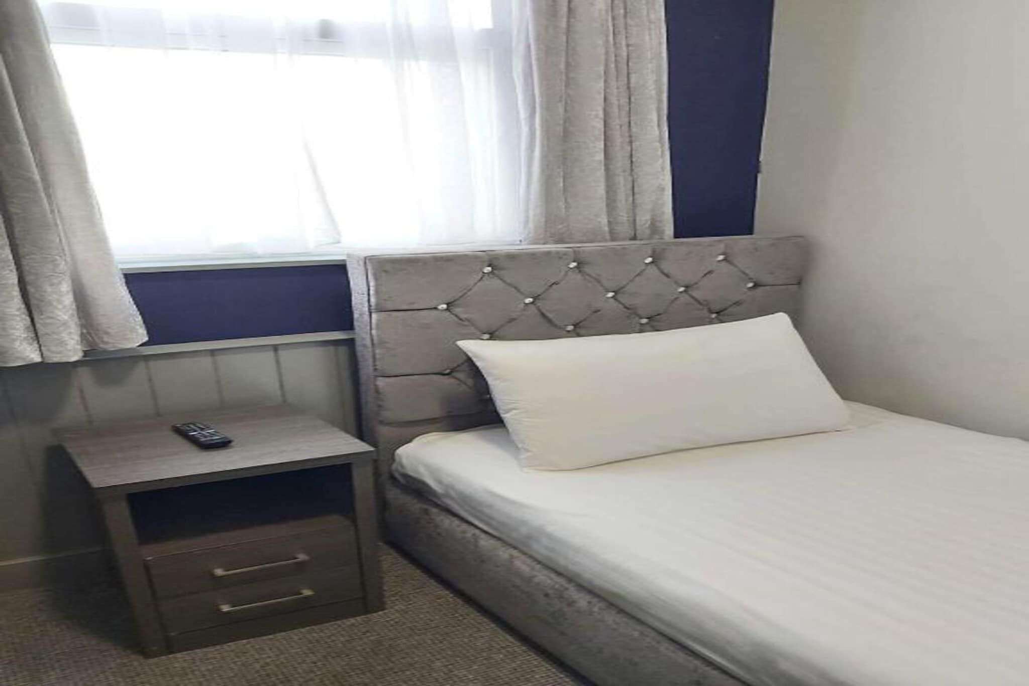 Une chambre à coucher avec un lit, une table de chevet et une fenêtre avec des rideaux.
