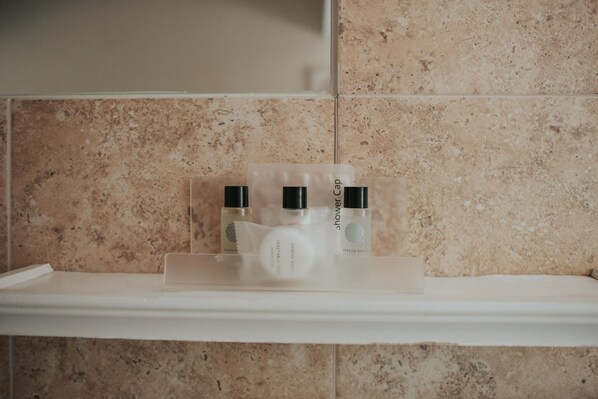 A bathroom shelf with three toiletry bottles and a shower cap. - Atlantic Tower hotel by Sunday Junior Suite (Liverpool)
