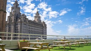 A rooftop terrace with picnic tables and a view of a historic building.