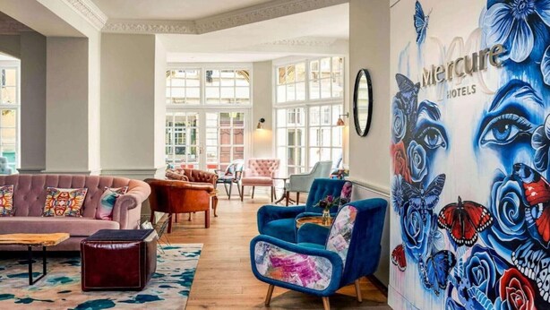 A spacious lobby with a large mural, comfortable seating, and large windows.