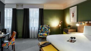 Ett hotellrum med en säng, ett skrivbord, en stol och en lampa.