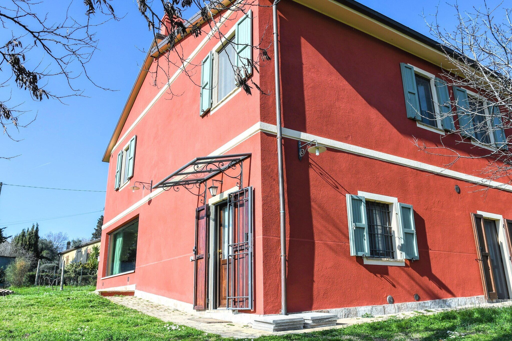 Un bâtiment rouge doté d’une grande fenêtre et d’une porte, entouré d’une zone herbeuse.