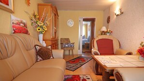 Een woonkamer met een beige bank, een houten tafel en een vloerkleed met bloemen.