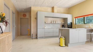 A modern kitchen with white cabinetry, a yellow trash bin, and a window with a view of trees. - Gorgeous home in Spøttrup with sauna (Spøttrup)