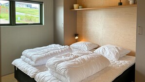 A bed with white bedding, a bedside lamp, and a window with a view of a grassy area. - Gorgeous home in Spøttrup with sauna (Spøttrup)