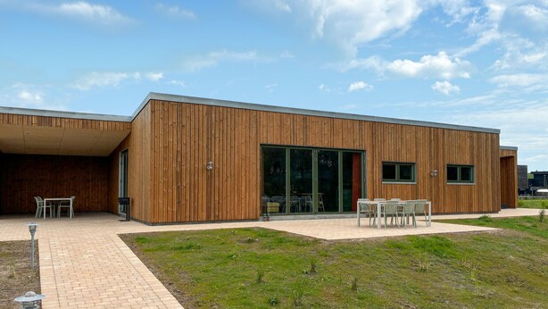 A modern building with a wooden facade, large glass doors, and outdoor seating. - Gorgeous home in Spøttrup with sauna (Spøttrup)