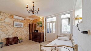 A bedroom with a stone wall, a bed, a dresser, a cabinet, and a chandelier. - Natur Olive House Ston (Ston)