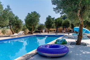 Una piscina con sillones de descanso y un tobogán de agua.