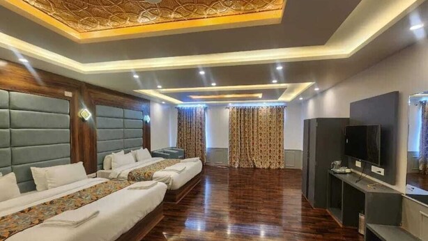 A hotel room with a large bed, a TV, and a wooden floor. - Hotel Town Star (Srinagar)