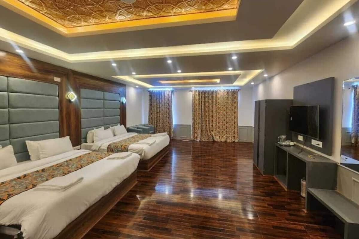 Quarto de hotel com uma cama grande, uma televisão e piso de madeira.