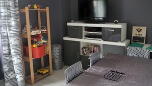 A bedroom with a bed, a TV, a bookshelf, and a desk.