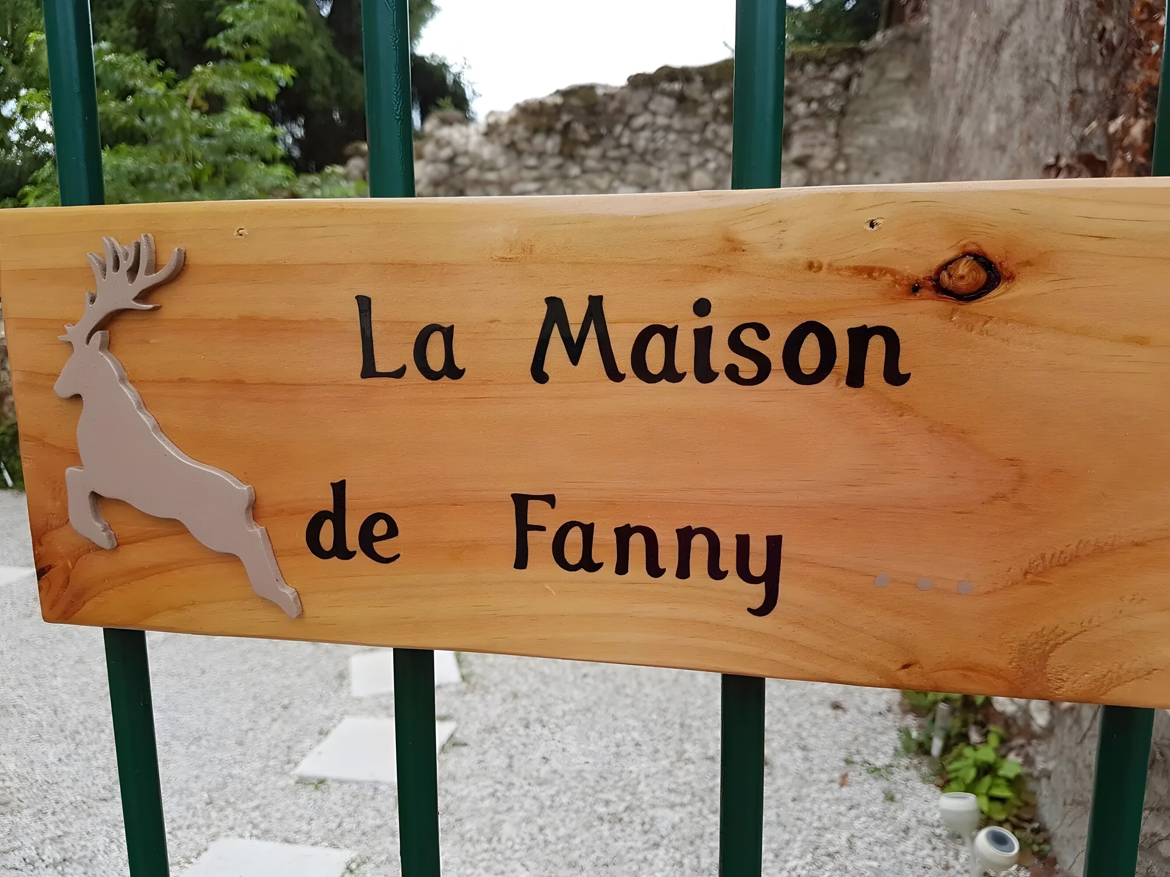 Une enseigne en bois représentant la silhouette d’un cerf et portant l’inscription « La Maison de Fanny ».