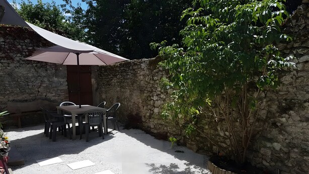 A patio with a table and chairs, a stone wall, and a potted plant.