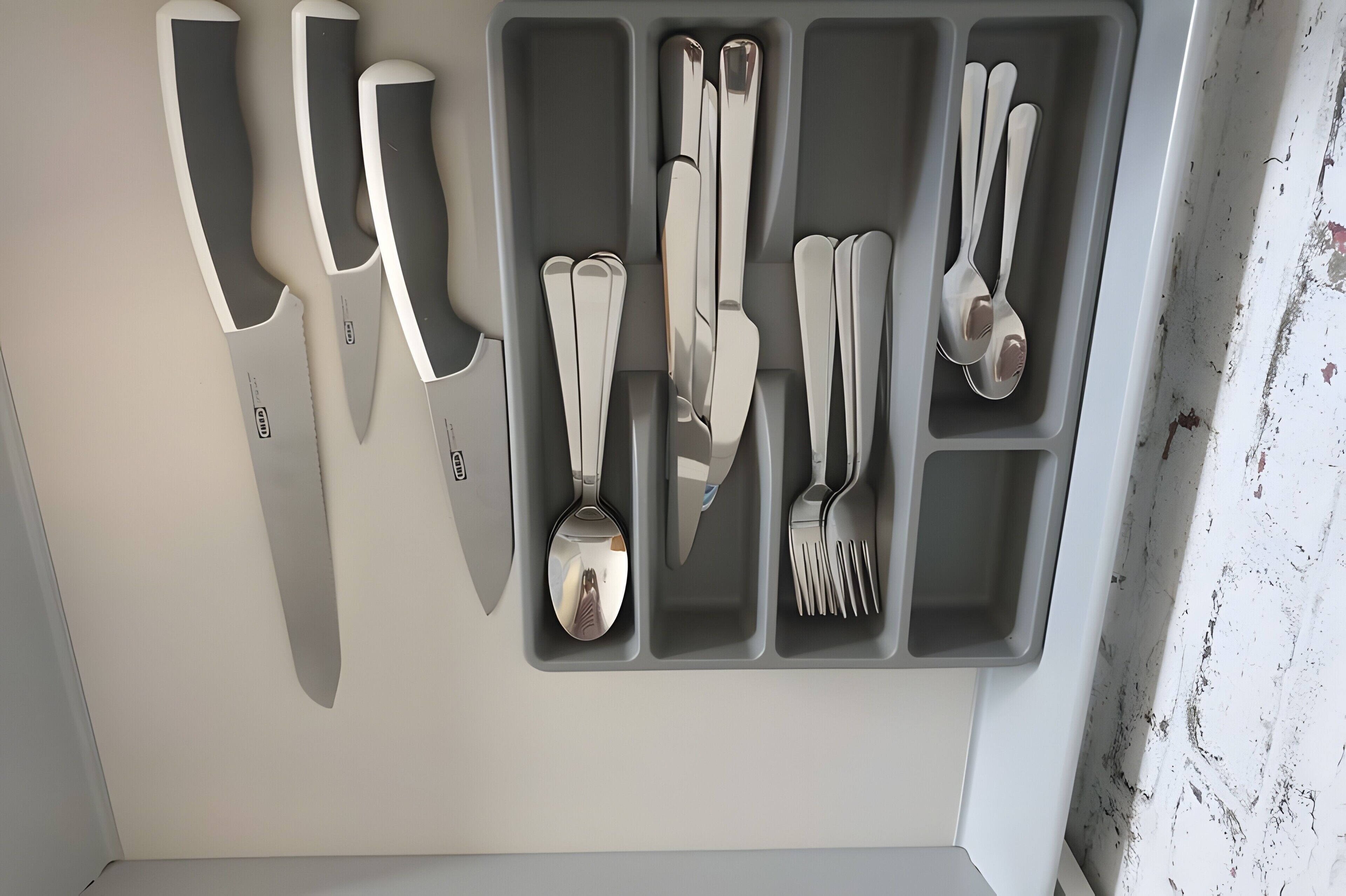 Un organizador de utensilios de cocina con cuchillos, cucharas y un tenedor.