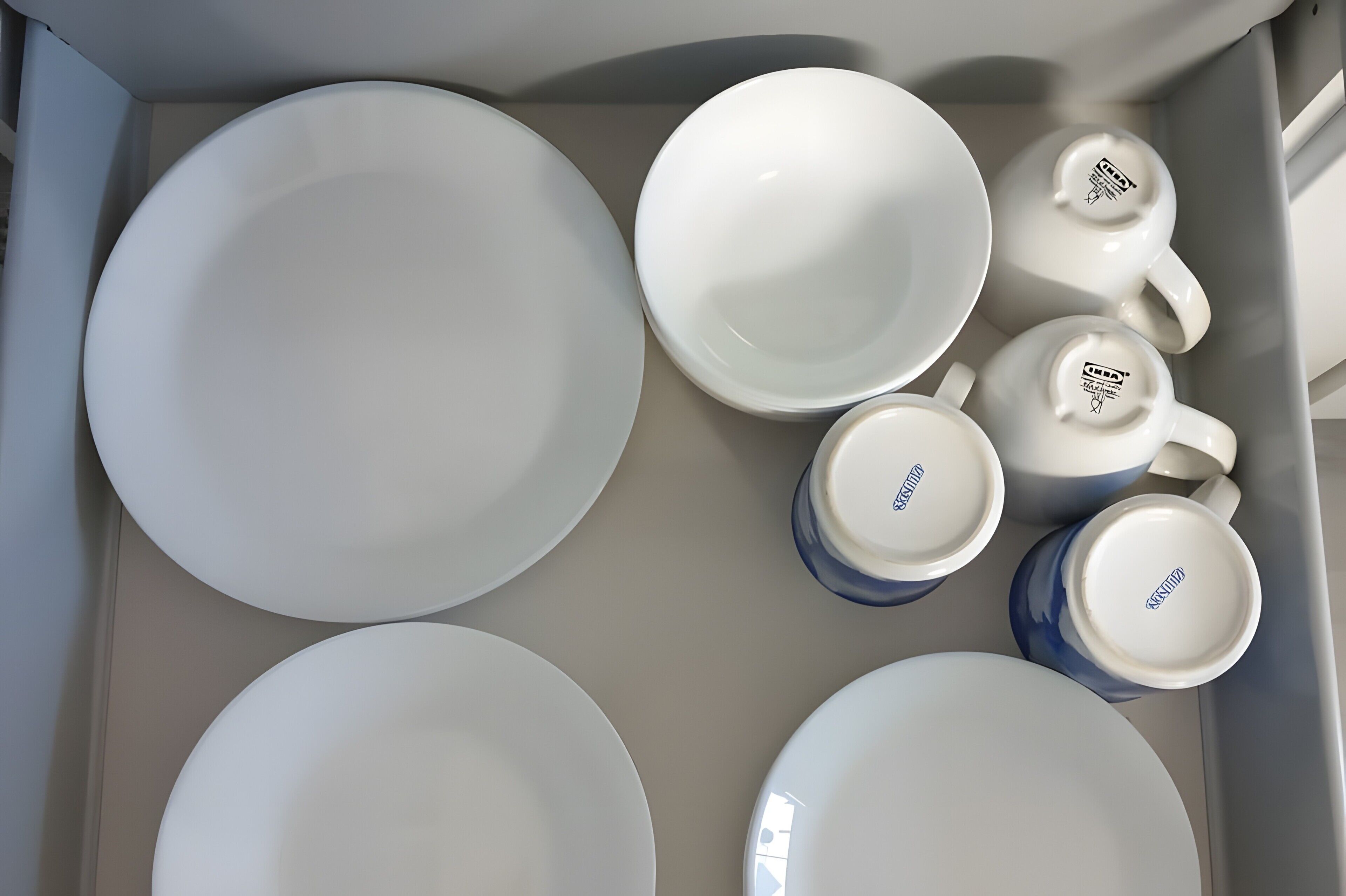 A set of white plates and cups with a logo, arranged in a box.