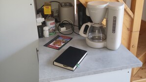 Un comptoir de cuisine avec une machine à café, un grille-pain, un livre et une boîte de thé Lipton.