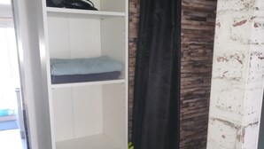 Une armoire blanche avec des étagères, un rideau noir et un comptoir en marbre.