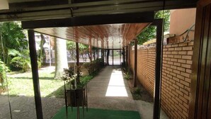 Um corredor interno com parede de tijolos, carpete verde e portão de metal.