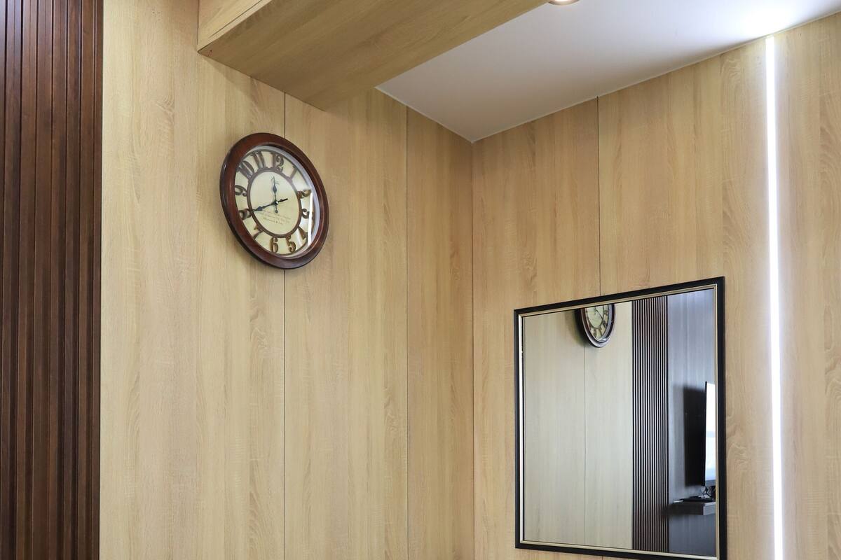 A room with wooden panel walls, a wooden bench, a clock, and a mirror.
