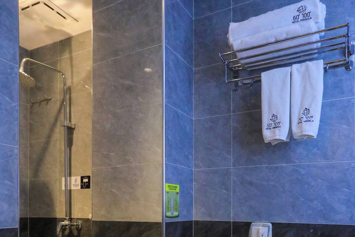 A modern bathroom with a walk-in shower, a toilet, and a towel rack with towels.