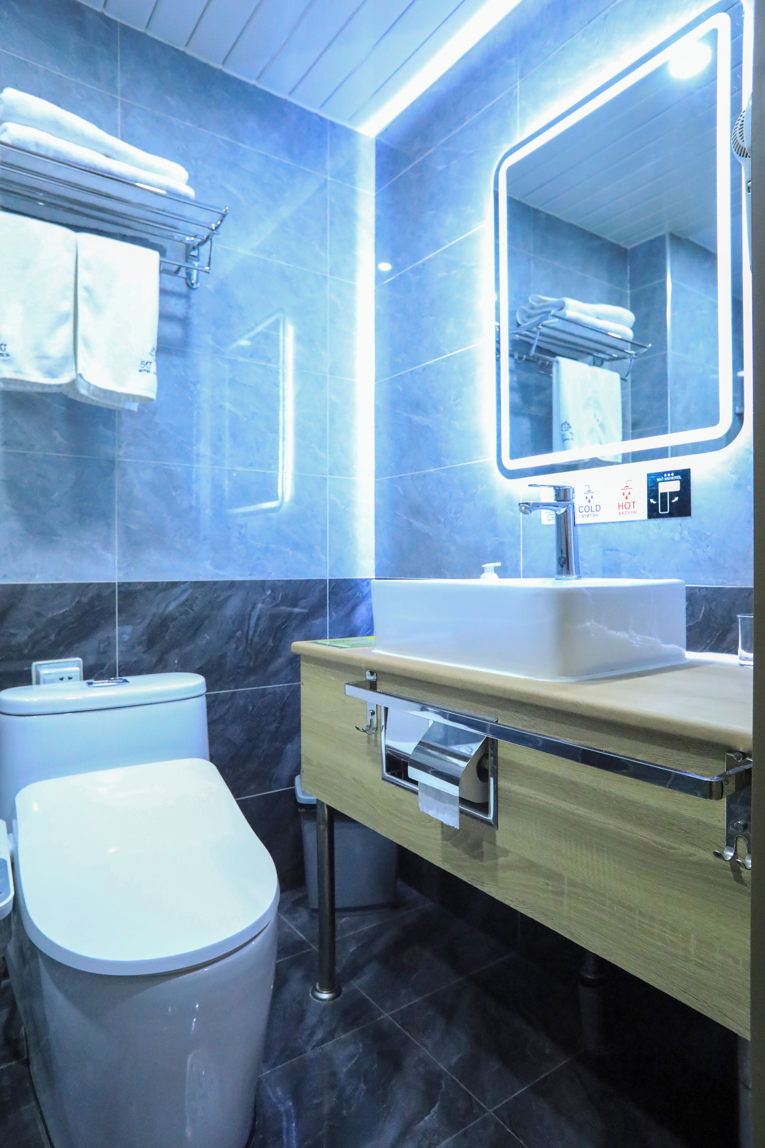 A modern bathroom with a marble floor, a sink with a mirror, and a toilet.