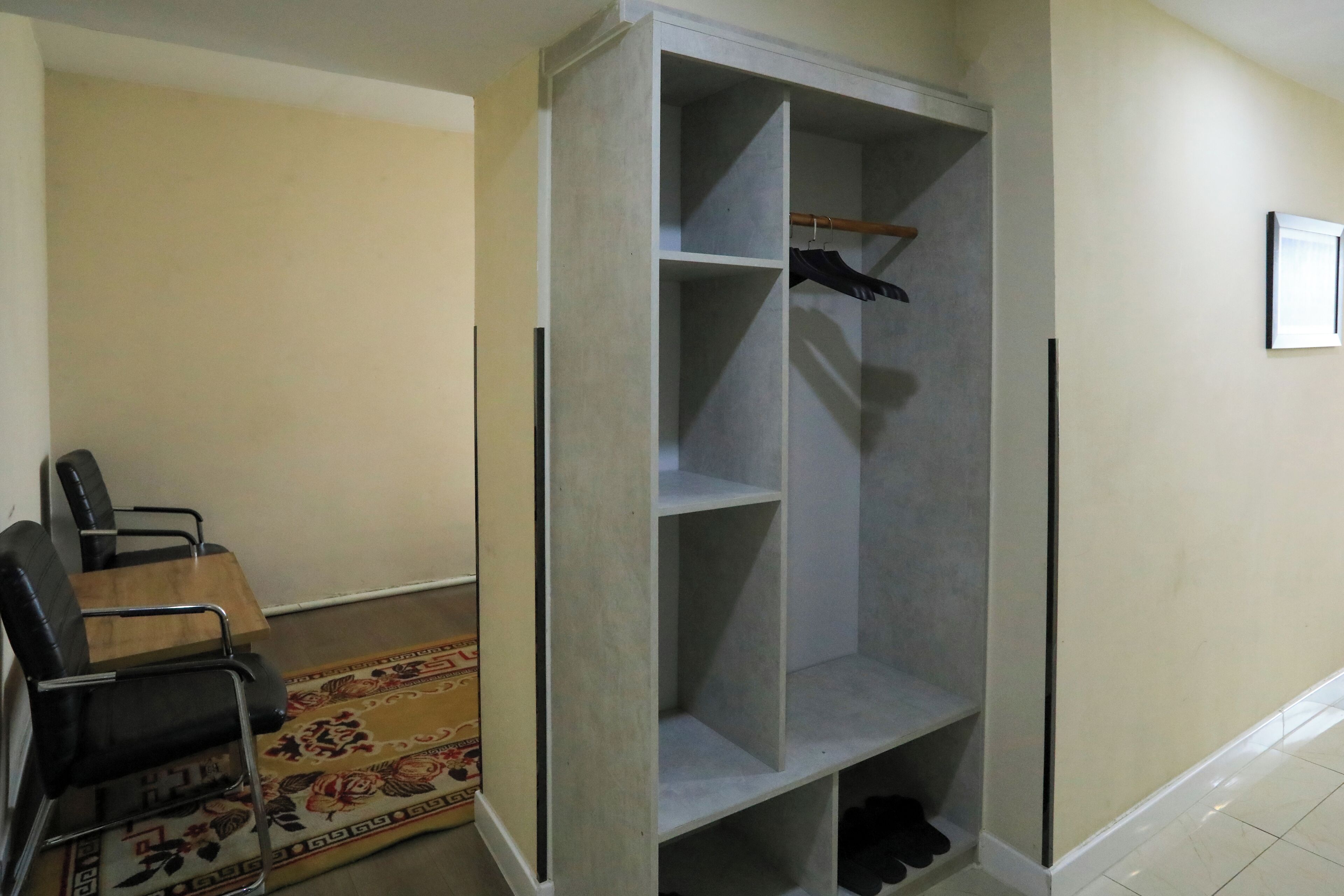Ein Zimmer mit einem grauen Wandschrank, einem Holzstuhl und einem gemusterten Teppich.