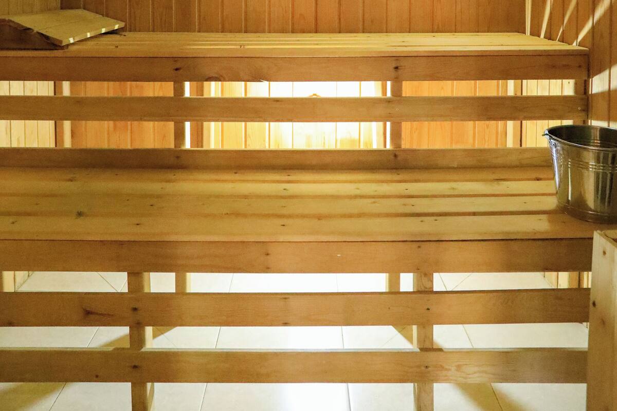 A wooden sauna with benches and a metal bucket.