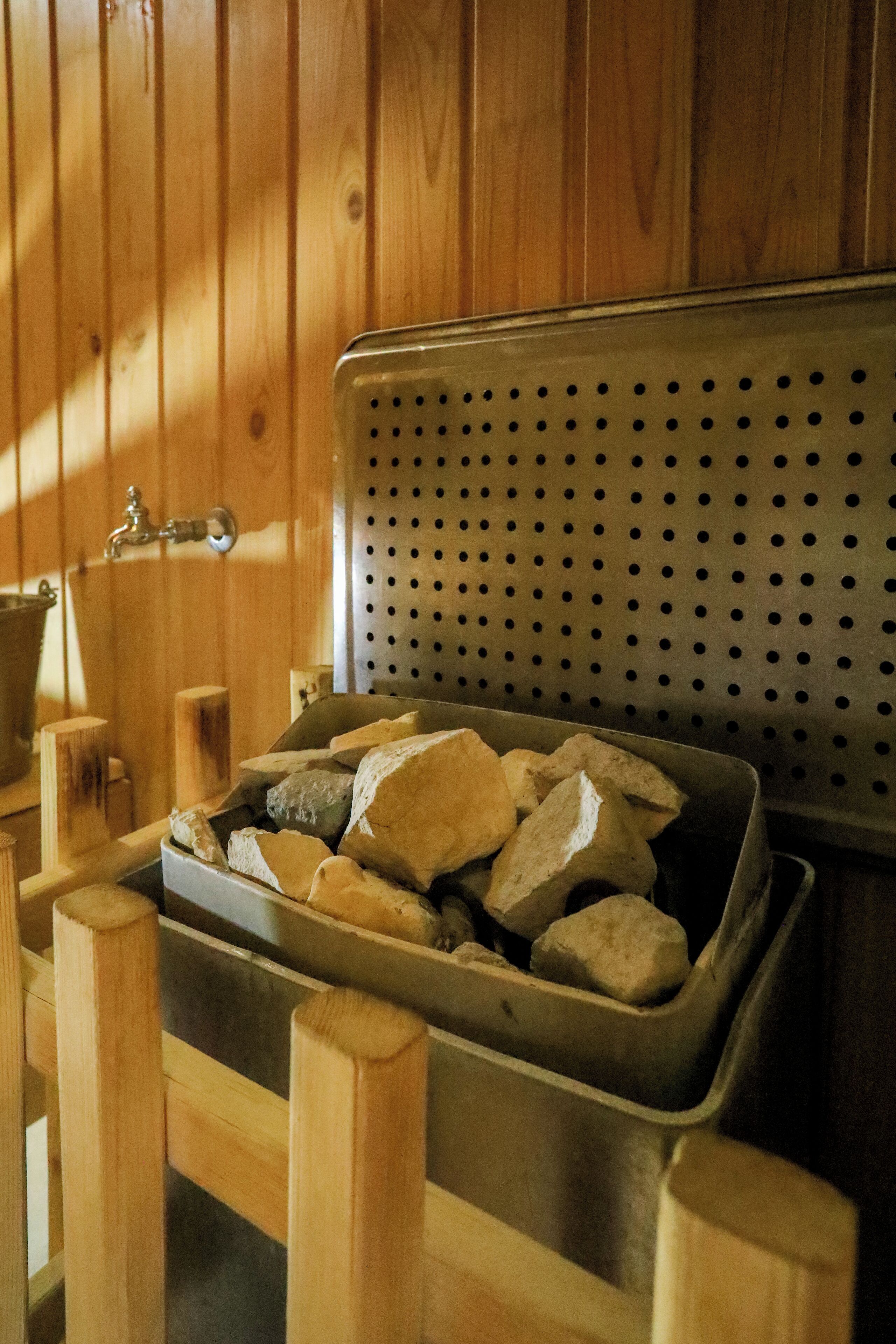 A metal bin with rocks, wooden posts, and a perforated metal panel in a wooden room.