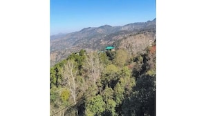 A mountainous landscape with a building with a green roof. - Hotel The Waypoint Inn (Shimla)