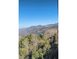 Un paisaje montañoso con un edificio de techo verde.