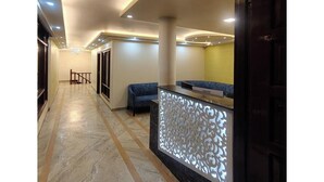 A hotel lobby with a reception desk, seating area, and a hallway leading to other rooms. - Hotel The Waypoint Inn (Shimla)
